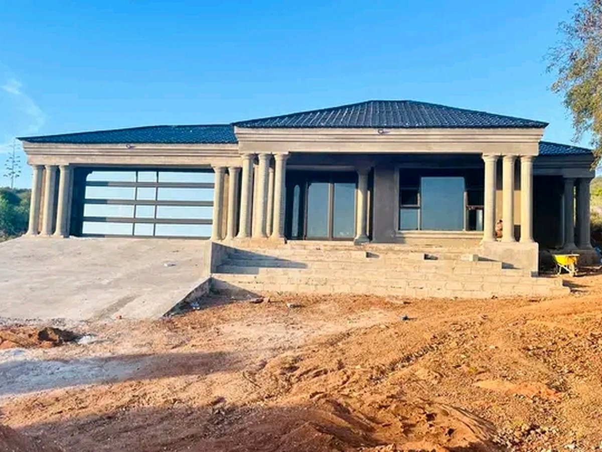 House with classical columns and glass garage door under construction