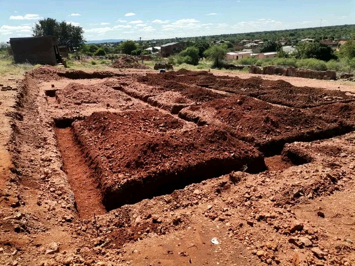 Foundation trenches excavated in red soil ready for concrete pouring